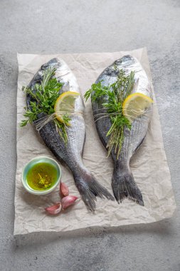 Dorada balığı, limonlu taze deniz çamı ve gri taşlı arka planda bitkiler, üst manzara..