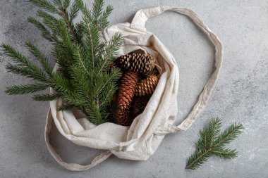 Sıfır Noel konsepti. Doğal Noel süslemeleri, çam kozalakları ve keten çantada dallar. Düz yatış, üst görünüm.