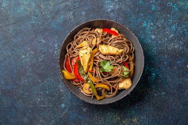Japon karabuğdaylı soba şehriyesi tavuk ve sebzeli havuç, dolma biber ve yeşil fasulye gri kasede, üst manzara, kopyalama alanı