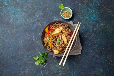 Japon karabuğdaylı soba şehriyesi tavuk ve sebzeli havuç, dolma biber ve yeşil fasulye gri kasede, üst manzara, kopyalama alanı