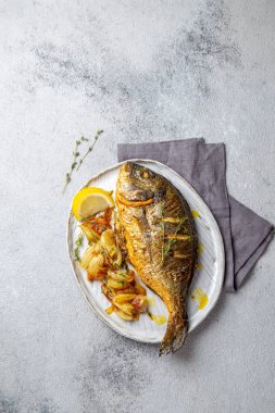 Izgara deniz çerezi ya da gri tabakta dorada. Gri arkaplan