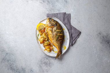 Izgara deniz çerezi ya da gri tabakta dorada. Gri arkaplan