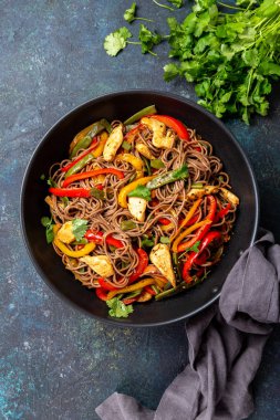 Japon karabuğdaylı soba eriştesi, tavuk ve sebzeli havuç, dolmalık biber ve lacivert arka planda yeşil fasulye.