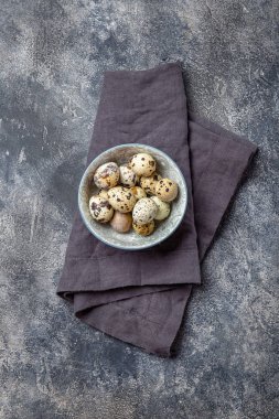 Quail eegs en bowl, gray background. Top view, copy space