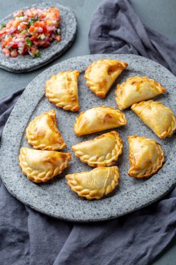 Domates sosu ve guacamole ile taş plaka üzerinde farklı küçük kokteyl Empanadas . Gri arka plan. Latin Amerika ve İspanyol tipical gıda.