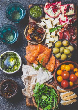 Meze. Şarap seti aperitif. Jambon Serrano, füme somon, kurutulmuş ve taze domates zeytin peyniri, gemide şarap. Üst görünüm, gri cncrete arka plan.