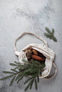Sıfır Noel konsepti. Doğal Noel süslemeleri, çam kozalakları ve keten çantada dallar. Düz yatış, üst görünüm