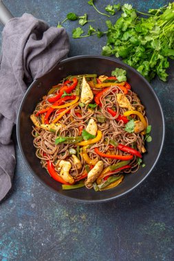 Japon karabuğdaylı soba eriştesi, tavuk ve sebzeli havuç, dolmalık biber ve lacivert arka planda yeşil fasulye..