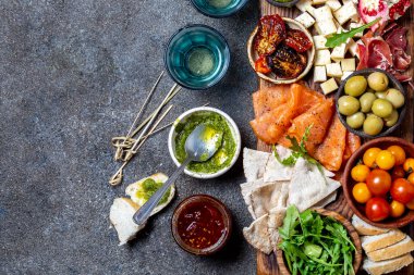 Meze. Şarap seti aperitif. Jambon Serrano, füme somon, kurutulmuş ve taze domates zeytin peyniri, gemide şarap. Üst görünüm, gri cncrete arka plan.