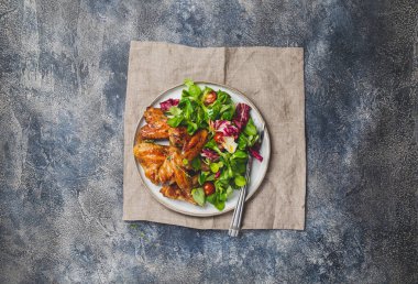 Kızarmış bbq kanatları ve domatesli yeşil salata. Üst görünüm.
