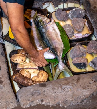 Paskalya Adası ton balığı, deniz ürünleri, tavuk, et ve sıcak taşın üzerinde hazırlanmış ve muz ağacı yapraklarıyla kaplı bir kamp yeri. Curanto rapa nui.