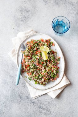 Beyaz kasede domatesli ve otlu Quinua salatası..