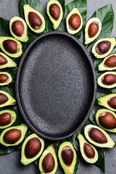 Avocado en avocado boom bladeren frame rond lege plaat. Kopieer ruimte voedsel achtergrond — Stockfoto