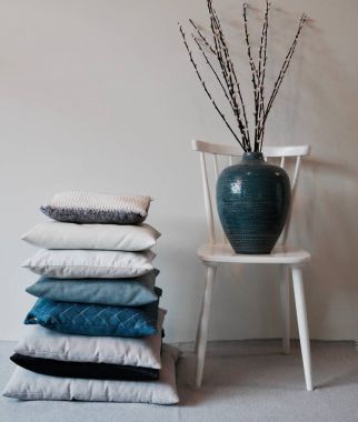 Stapel kussens en blauwe vaas met takken