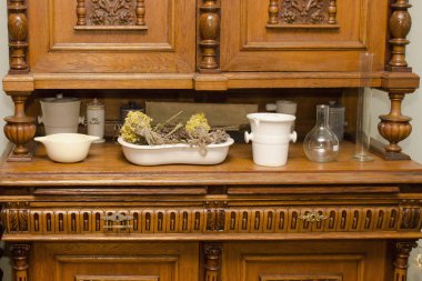 Antika eczane gereçleri ve ahşap dolabın üstündeki kurutulmuş bitkiler.