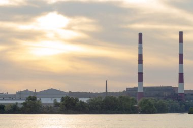Gün batımında sanayi kuleleri olan bitkilerin yeşillik manzarası