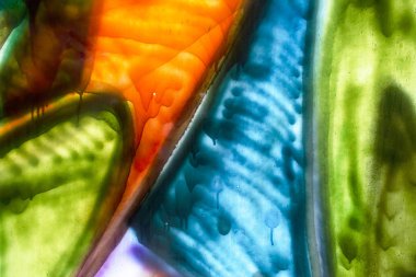 Camdaki mavi, turuncu ve yeşil renklerin soyut desenleri.