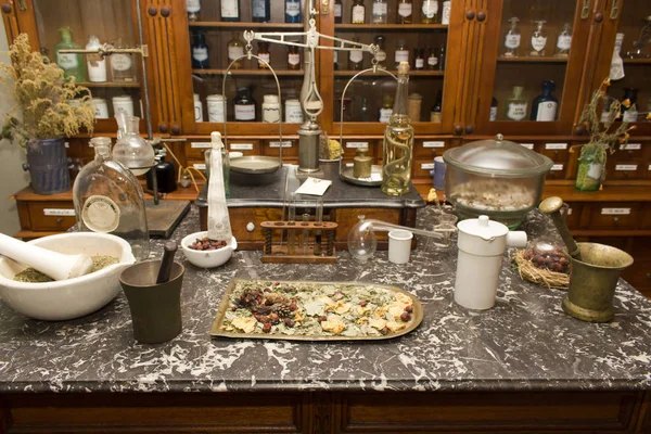 A table with antique instruments for making medicines against the background of stored preparations in a cabinet — 스톡 사진