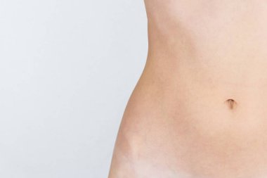 Gri, beyaz arka planda izole edilmiş ince, ince, güzel bir kız göbeği var, boş bir yer var.