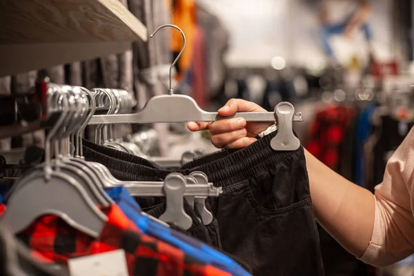 Mujer joven eligiendo la ropa en el enorme centro comercial durante las grandes ventas — Foto de Stock