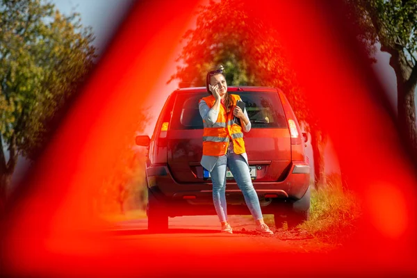Mujer joven enojada en una situación de peligro vial: establecer un triángulo de advertencia y pedir ayuda — Foto de Stock