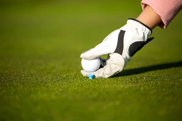 Professionell golfspelare som ställer upp golfbollen på ett stativ på gräs under golfmatchen — Stockfoto