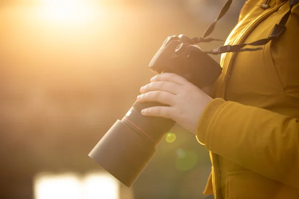 Ung kvinna fotograf med professionell camer i handen under solnedgången — Stockfoto