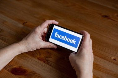 Cep telefonundaki Facebook logosu uygulama ekranı çevrimiçi perakende hizmeti, eller