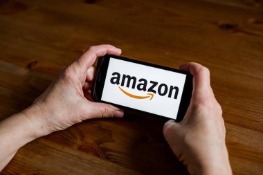 Amazon logosu uygulama ekranını cep telefonunda çevrimiçi perakende hizmeti, eller