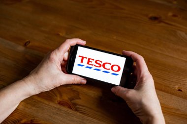 Tesco logo uygulama ekranını cep telefonunda çevrimiçi perakende hizmeti, eller