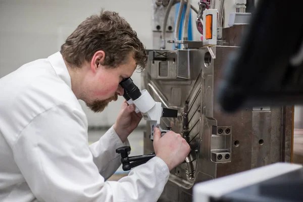 Quality engineer checks deficiencies on the injection mold by a microscope, industrial concept — Stock Photo, Image