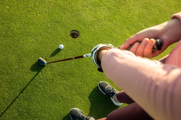 Söt ung kvinna spelar golf på träningsplats, träffar golfbollen i hålet, sport koncept — Stockfoto