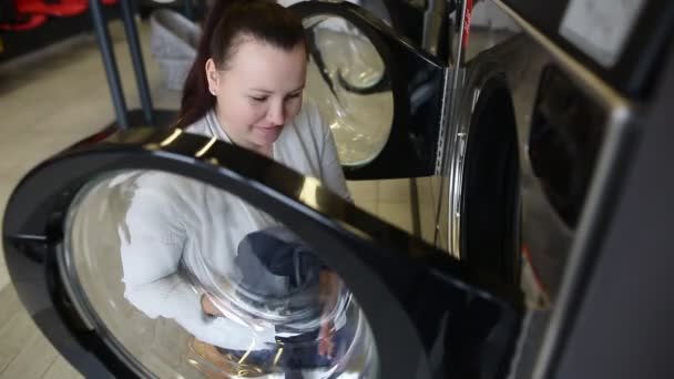 Pretty young woman putting, getting some dirty clothes into a washing machine in a laundry, laundry cleaning — Stock Video