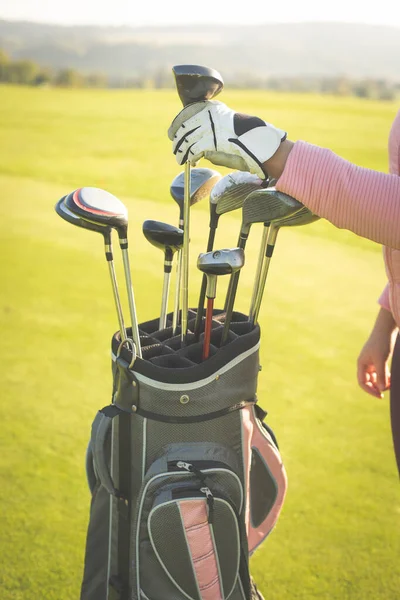 Mulher mãos escolhendo tacos de golfe a partir do saco de golfe, conceito de esporte — Fotografia de Stock