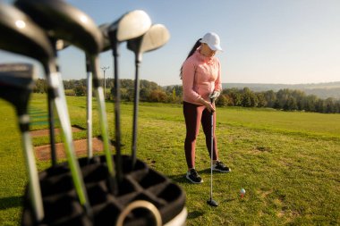 Woman golf beginner trying to play golf on the training golf ground, sport concept