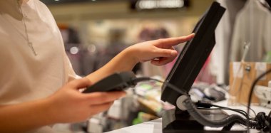 Saleswoman doing process payment on touchscreen pos, counting sale, finance concept