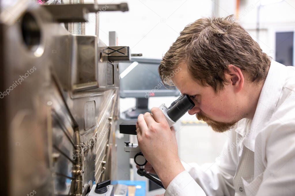 quality engineer checks deficiencies on the injection mold by a microscope, industrial concept
