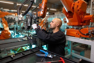 Otomotiv endüstriyel, akıllı bir fabrikada otomatik robot silahlarının bakımını yapan bir mühendis.