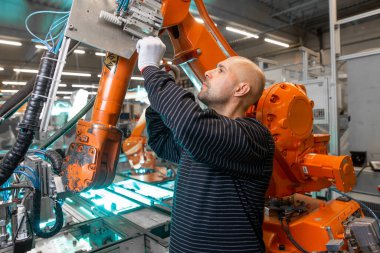 Otomotiv endüstriyel, akıllı bir fabrikada otomatik robot silahlarının bakımını yapan bir mühendis.