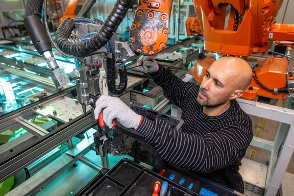 Otomotiv endüstriyel, akıllı bir fabrikada otomatik robot silahlarının bakımını yapan bir mühendis.