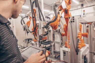 Otomotiv endüstrisinde, akıllı fabrikada, otomatik işyerinde otomatik robotla çalışan mühendis ve teknisyen.