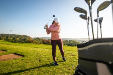 Yeni başlayan bayan golfçü antrenman sahasında golf oynuyor, spor anlayışı.