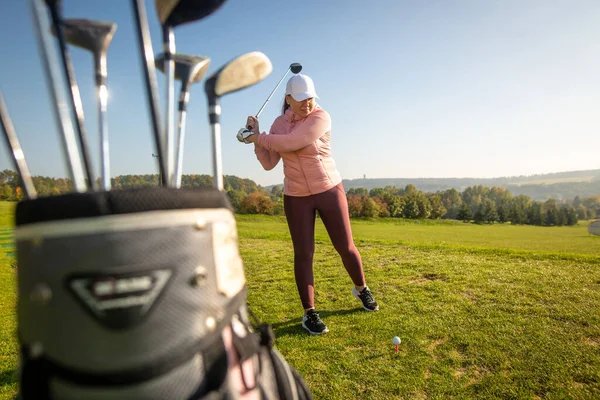 Yeni başlayan bayan golfçü antrenman sahasında golf oynuyor, spor anlayışı.