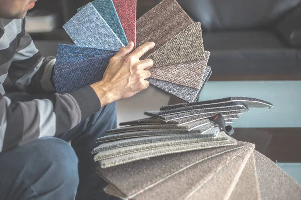 Homme choisissant la bonne couleur et le bon matériau de tapis pour son nouvel appartement dans le studio de plancher, l'ameublement des ménages — Photo