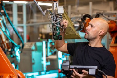 Akıllı otomotiv fabrikasında otomatik robot silahları için bakım yapan mühendis, endüstriyel konsept