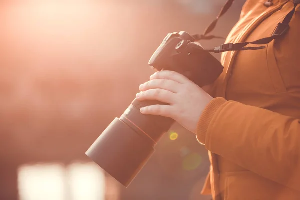 Närbild av kvinnlig professionell fotograf med DSLR kamera i handen under härlig sommar solnedgång, fotografering koncept — Stockfoto