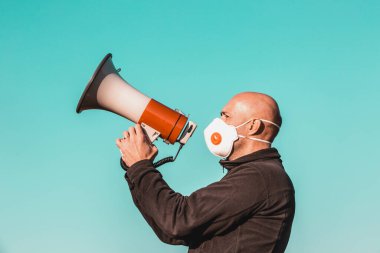 Coronavirus salgını, tıbbi maskeli kızgın adam megafona, koronavirüse, covid-2019 protestosuna, ekonomik krize, dünya çapında salgına haykırıyor.