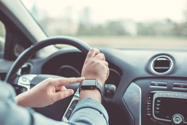 Primer plano de la mujer que utiliza reloj inteligente durante la conducción de su coche, concepto de transporte —  Fotos de Stock