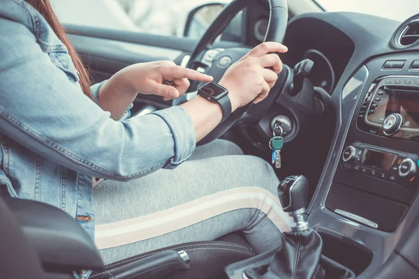 Primer plano de la mujer que utiliza reloj inteligente durante la conducción de su coche, concepto de transporte —  Fotos de Stock