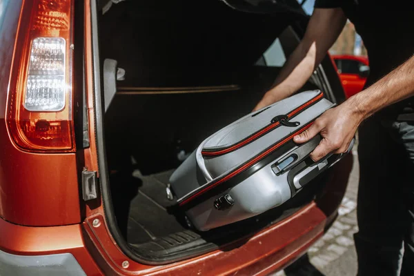 Hombre de negocios, empleado preparándose para el viaje de negocios al extranjero, pone el equipaje en el maletero de un coche — Foto de Stock
